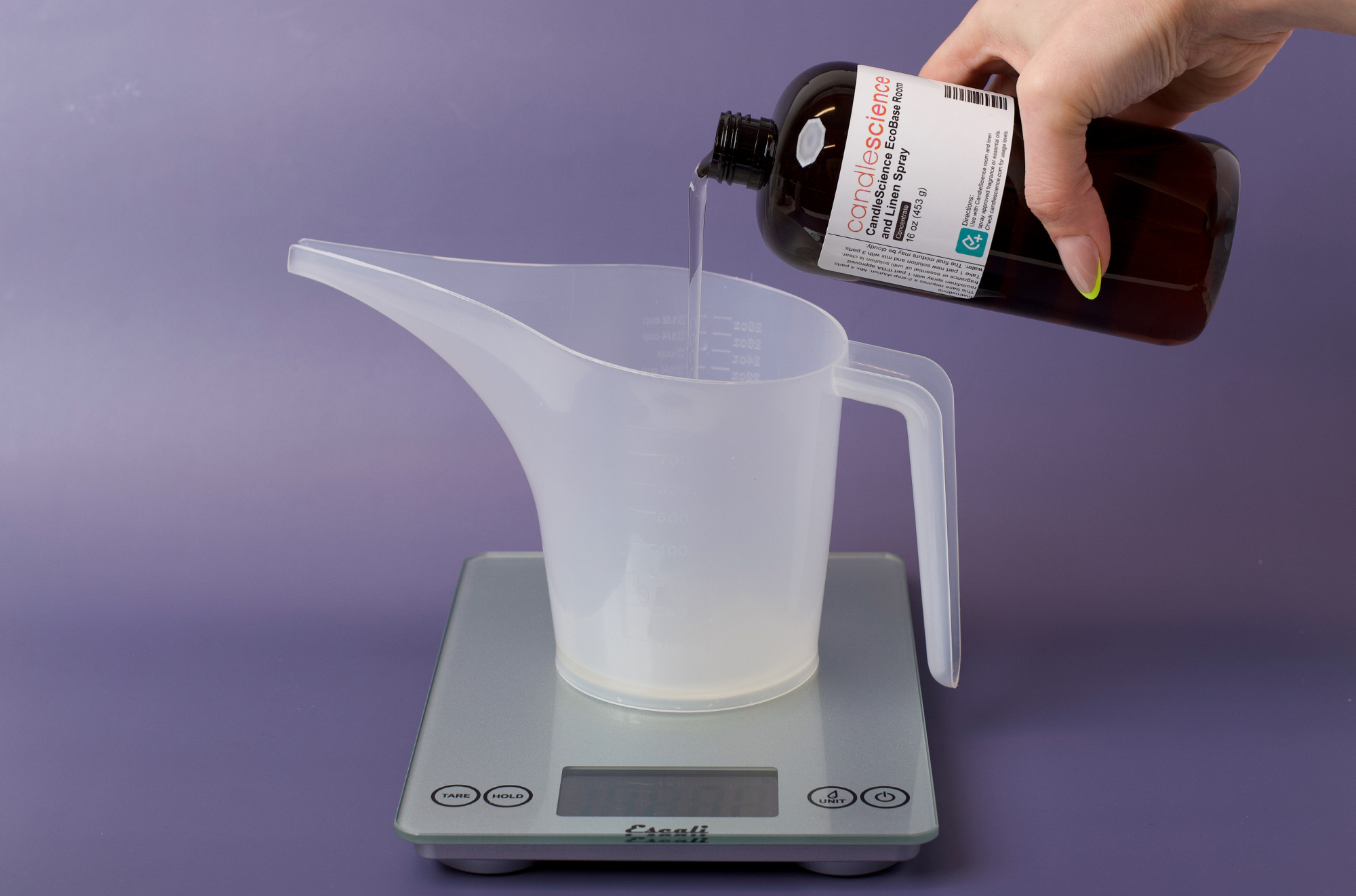 Pouring room spray base into funnel pouring pitcher on scale.